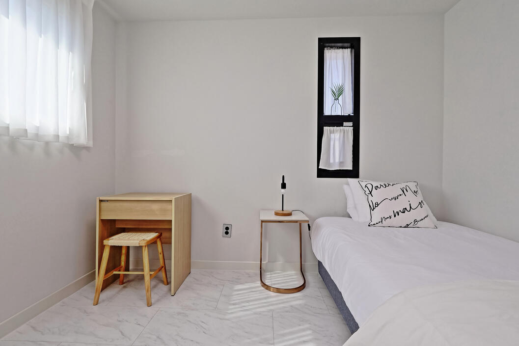 The second bedroom includes a Super-single bed, night stand with lamp, vanity and clothes rack.