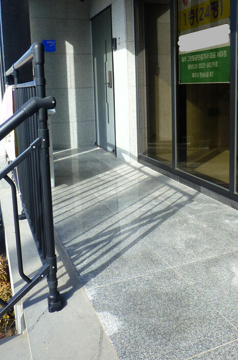 The door of the building is the metal door on your left